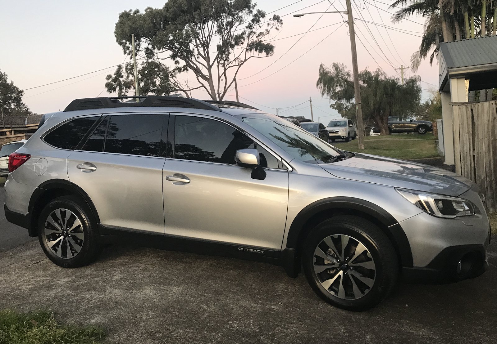 A silver Subaru Outback wagon parked on a driveway at dusk